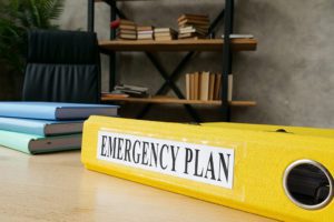 yellow binder in front of bookshelf about disaster emergency plan and security technology